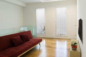 uma sala de estar com um sofá vermelho e duas janelas em Araba Fenice em Lecce
