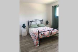 - une chambre dotée d'un lit avec un couvre-lit floral dans l'établissement Aux portes de La Rochelle - Un air de campagne au bord de mer, à Marsilly
