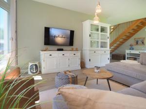 a living room with a tv on a white cabinet at Fischerhus Loddin mit Sauna und Kamin in Loddin