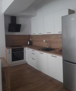 a kitchen with white cabinets and a stainless steel refrigerator at Apartamenty Irena Stare Miasto Św. Ducha in Elblag