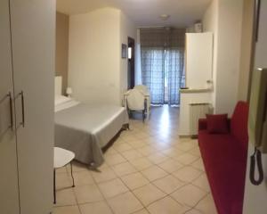 a hotel room with a bed and a red chair at monolocale speedy in Fiumicino