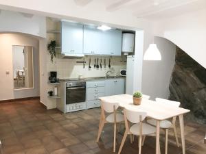 a kitchen with white cabinets and a table and chairs at Planta baja centro Cadaqués in Cadaqués