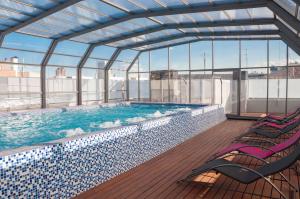 a large swimming pool with two chairs in a building at Funway Academic Resort in Madrid