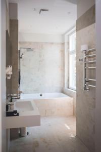 uma casa de banho branca com uma banheira e um lavatório em Roze Boutique Hotel em Liepāja