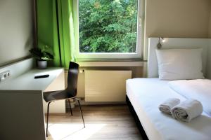 a bedroom with a bed and a desk and a window at Bendorf Hotel by Belvilla in Bendorf