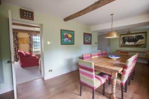 a dining room with a wooden table and pink chairs at Yellison at Broughton Sanctuary in Skipton