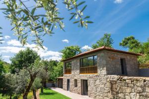 a stone house with a stone wall and trees at Casa Velha de Ponta Sôto in Cela