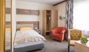 ein Schlafzimmer mit einem Bett und einem Stuhl in der Unterkunft Garten-Hotel Ochensberger in Sankt Ruprecht an der Raab