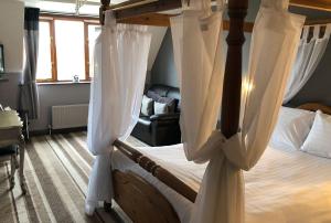 1 dormitorio con cama con dosel y cortinas blancas en The Airman Hotel, en Shefford