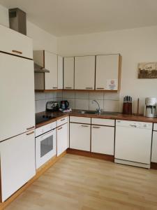 a kitchen with white appliances and a wooden floor at Haus Matthias in Umhausen