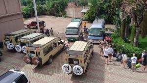 un groupe de véhicules garés dans une rue avec des gens dans l'établissement The Charity Hotel International, à Arusha