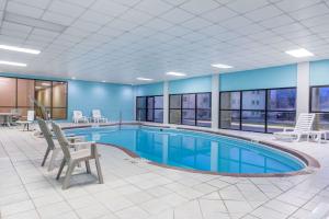 a pool in a hotel room with chairs and tables at Baymont by Wyndham Kokomo in Kokomo