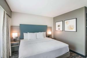 a bedroom with a large white bed and two lamps at Hourglass Hotel, Ascend Hotel Collection in Bakersfield