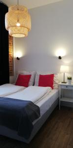 a bedroom with a bed with red pillows and a chandelier at Rooms by Apartamenty Lubartowska Street in Lublin