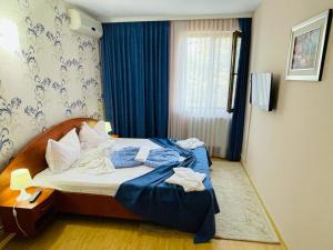 a hotel room with a bed with blue sheets and a window at Hotel Turist in Neptun