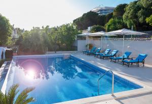 a swimming pool with blue chairs and umbrellas at 5 Bedroom Villa with Private Pool in Poljice