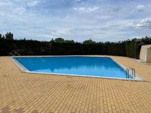 une grande piscine bleue installée sur une cour en briques dans l'établissement Résidence port venus -au village naturiste -avec une vue sur le port et la mer, au Cap d'Agde