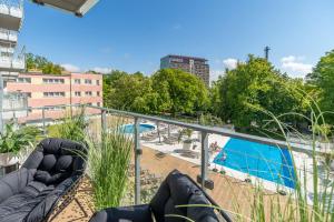 a balcony with a view of a pool and buildings at Apartamenty Fenomen - Premium Porto, Nadmorskie Tarasy FREE PARKING, SWIMMING POOL, SAUNA AND OTHER! in Kołobrzeg