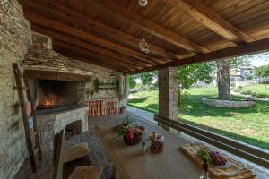 an outdoor patio with a stone fireplace and a table at Villa Bendek in Bokordići