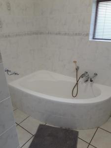 een badkamer met een wit bad en een raam bij Leisure@Loerie in Sedgefield