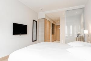 1 dormitorio con 1 cama y TV en la pared en Starling Hôtel Résidence Genève en Ginebra