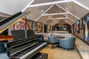 a piano in a room with chairs and paintings at Twr y Felin Hotel in St. Davids