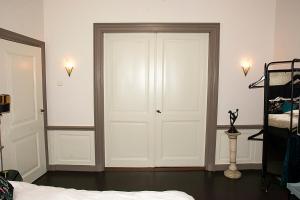- une chambre avec des portes blanches et un lit dans l'établissement B&B Belle Chambre - Luxe in Art Deco stijl, à Dordrecht
