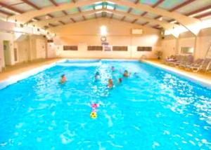 a group of people in a large swimming pool at Clifftop Chalet With Pool in Deal