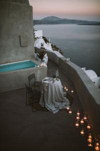 a table with candles next to a swimming pool at Spitia Santorini Villa Collection in Oia