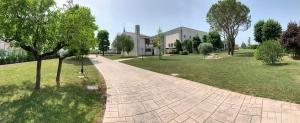 a brick path in a park with trees and a building at LOCANDA L'OFFICINA in Ceggia