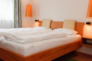 Una cama con sábanas blancas y almohadas. en Ferienwohnung Rhönchalet und TBund, en Fladungen