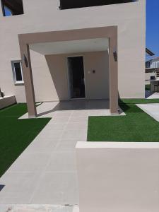 un gran edificio blanco con un patio con césped verde en Universe House en Dhromolaxia