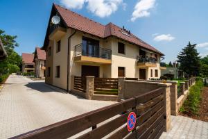 a house with a wooden fence in front of it at Captain’s Home Kenese Apartman in Balatonkenese