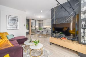 - un salon avec un canapé et une grande télévision dans l'établissement Apartamenty Fenomen - Premium Porto, Nadmorskie Tarasy FREE PARKING, SWIMMING POOL, SAUNA AND OTHER!, à Kołobrzeg