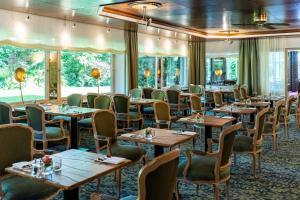 - une salle à manger avec des tables, des chaises et des fenêtres dans l'établissement Waldhotel Tannenhäuschen, à Wesel