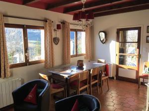 comedor con mesa, sillas y ventanas en Chalet Lou Griou, en Saint-Jacques-des-Blats