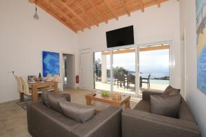 a living room with a couch and a table with a television at Sunset Sea View Villa 2 in Agios Georgios