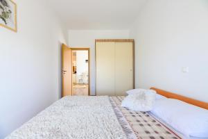 um quarto branco com uma cama e um espelho em Apartments Anita em Bibinje