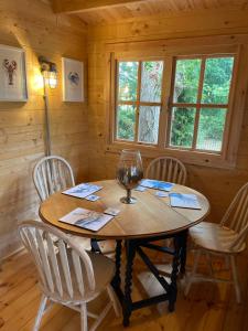 een houten tafel met stoelen en een wijnglas erop bij O Dan Y Coed Swedish Log Cabin with New 2024 Wood Fired Hot Tub in Chwilog