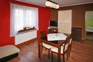 a dining room with a table and chairs and a red wall at Leniuchowo in Junoszyno