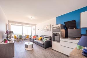 a kitchen and living room with a couch and a table at Les Vagues in Courseulles-sur-Mer +4 photos