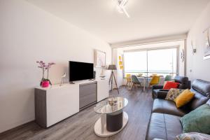 a living room with a couch and a tv at Les Vagues in Courseulles-sur-Mer