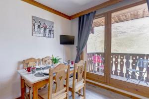 a dining room with a table and chairs and a window at Les Valmonts 403 in Les Menuires