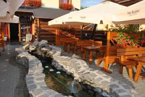 a restaurant with tables and benches and a water feature at Juliu's Panzio Csikszereda in Miercurea-Ciuc