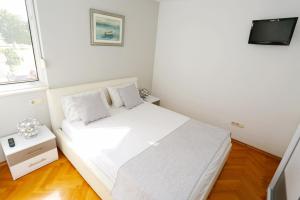 een kleine slaapkamer met een wit bed en een televisie bij Luxury Family Apartment Omiš in Omiš