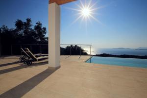 a patio with a view of a pool and the sun at Sunset Sea View Villa 2 in Agios Georgios
