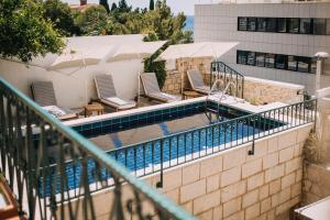 a swimming pool with chairs and umbrellas next to a building at Villa Allure of Dubrovnik in Dubrovnik