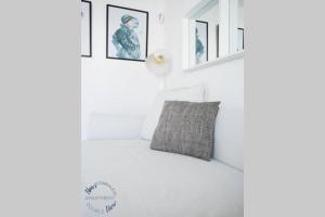 Dormitorio blanco con almohada gris y cuadros en la pared en Sunny Noa's apartment double pool view- wifi fibra by Rentalfue, en Corralejo