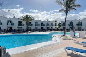 una piscina frente a un hotel con palmeras en Sunny Noa's apartment double pool view- wifi fibra by Rentalfue, en Corralejo