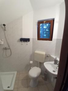 La salle de bains est pourvue de toilettes, d'un lavabo et d'une fenêtre. dans l'établissement Elo Apartman, à Csokonyavisonta